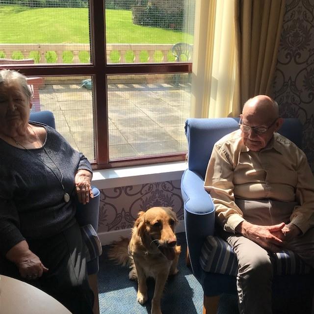 Foxy the therapy dog sitting between two tenants